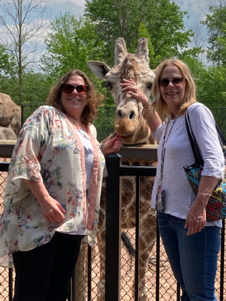 two women petting giraffe at the zoo