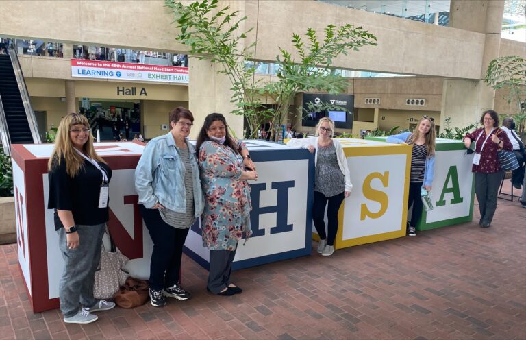 women posing with exhibit at convention