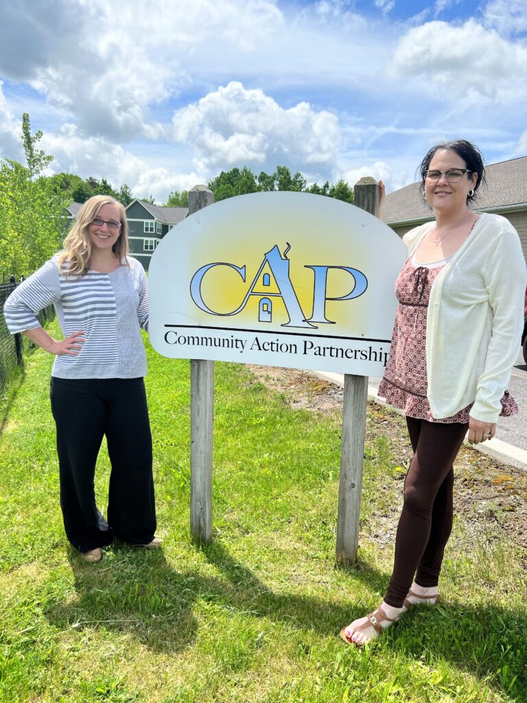 two women posing next to cap sign